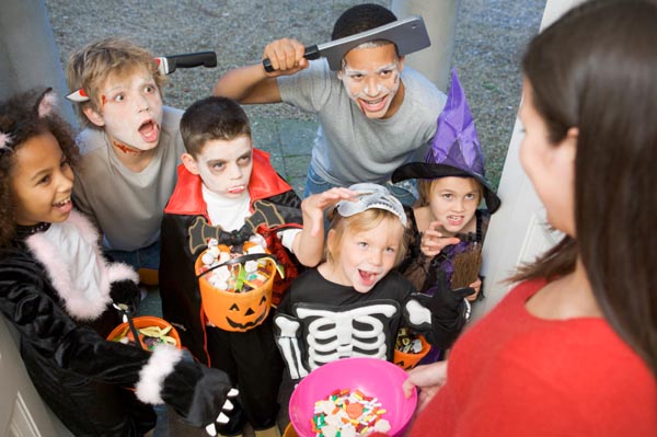 Six children in costumes trick or treating at womans house